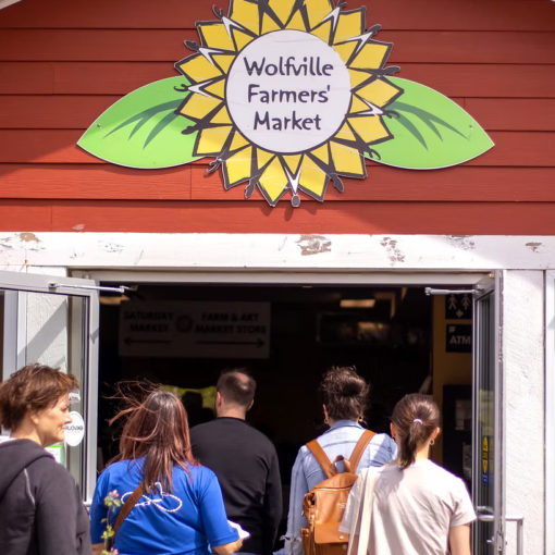 Group of people walking through the enterance to the Wolfville Farmers Market