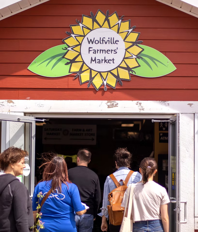 Group of people walking through the enterance to the Wolfville Farmers Market